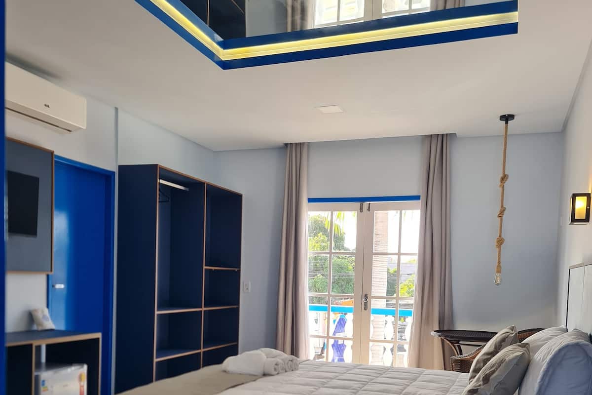 Ein Schlafzimmer mit einem großen Bett, einem Kleiderschrank, einem Schreibtisch und einem Fenster mit Vorhängen.