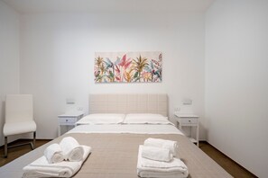 Une chambre d’hôtel comprenant un lit, deux tables de chevet, une chaise et une œuvre d’art murale.