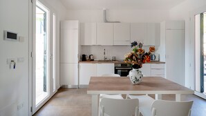 Eine moderne Küche mit weißen Schränken, einem Holztisch und einer Vase mit Blumen.