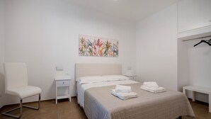 Ein Hotelzimmer mit Bett, Sessel, Nachttisch, Bank und einem Wandbild.