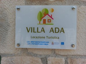 Une enseigne pour «VILLA ADA» avec un logo, le nom et les coordonnées.