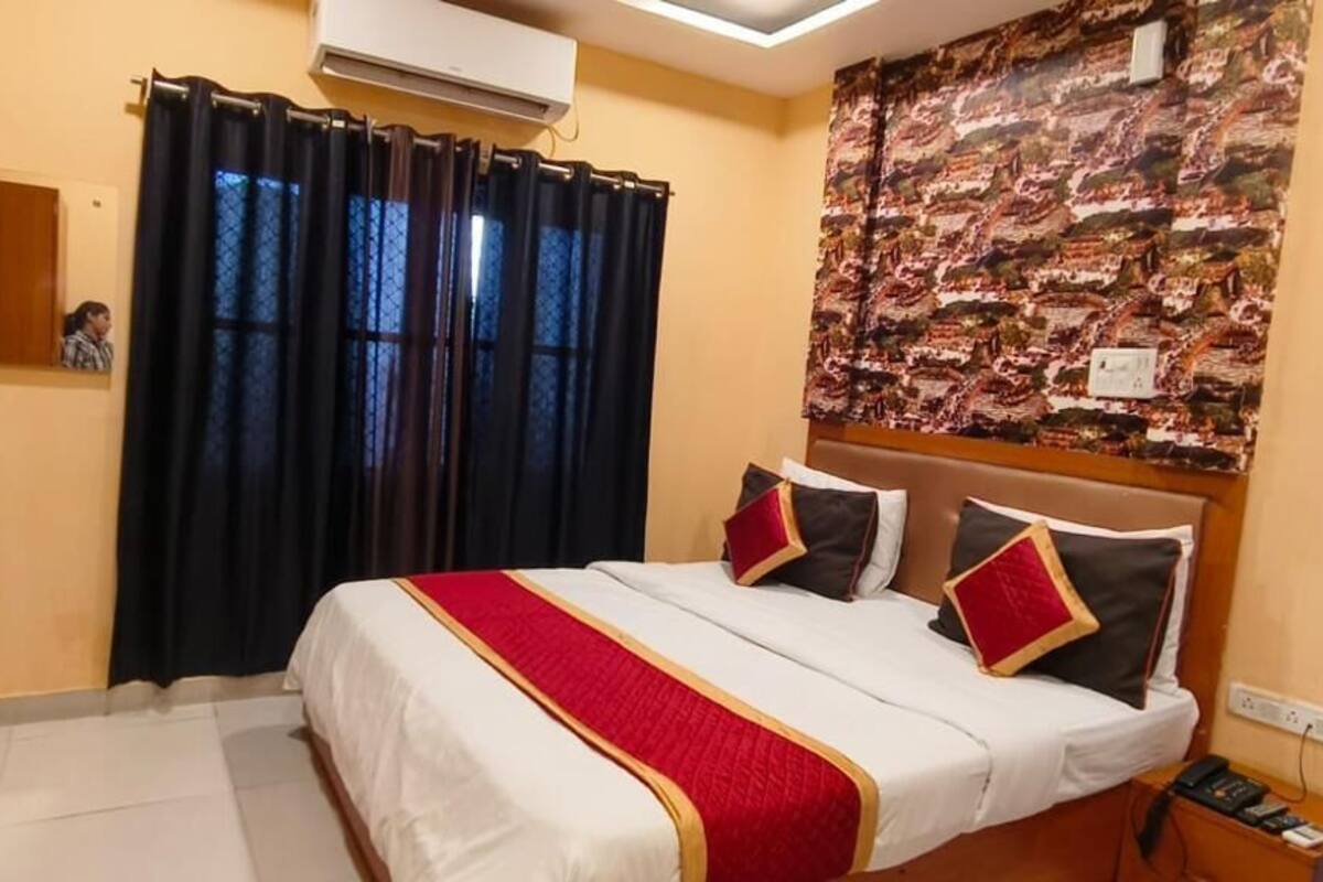 Une chambre d’hôtel comprenant un lit, un bureau, un miroir et un mur orné d’un motif texturé.
