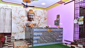 A reception area with a marble wall, a Buddha statue, a reception desk, and a checkered floor. - Arunai Grand Tiruvannamalai (Tiruvannamalai)