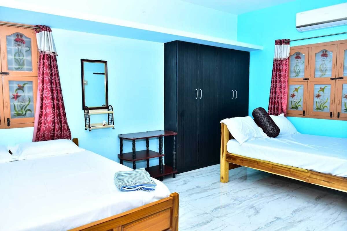 Une chambre d’hôtel avec deux lits simples, une armoire, une petite table et un miroir.
