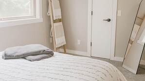 Un dormitorio con una cama grande, una ventana, una puerta y un espejo.