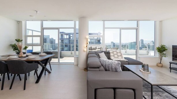 Ein modernes Wohnzimmer mit Essbereich, großen Fenstern und Blick auf die Stadt.