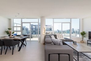 Een moderne woonkamer met een eethoek, grote ramen en uitzicht op de stad.