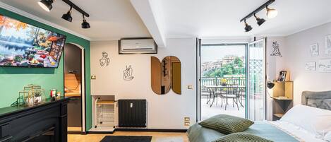 Une chambre moderne avec un lit, une télévision, une cheminée et un balcon équipé d’une table et de chaises.