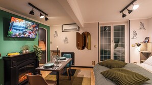 A modern bedroom with a fireplace, a dining area, and a large bed with green pillows. - 4BNB - Loft del Papa (Rome)