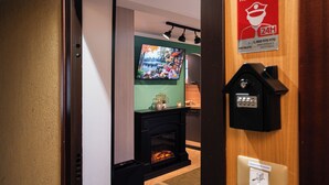 A hotel room with a fireplace, a television mounted on the wall, and a security keypad on the door. - 4BNB - Loft del Papa (Rome)