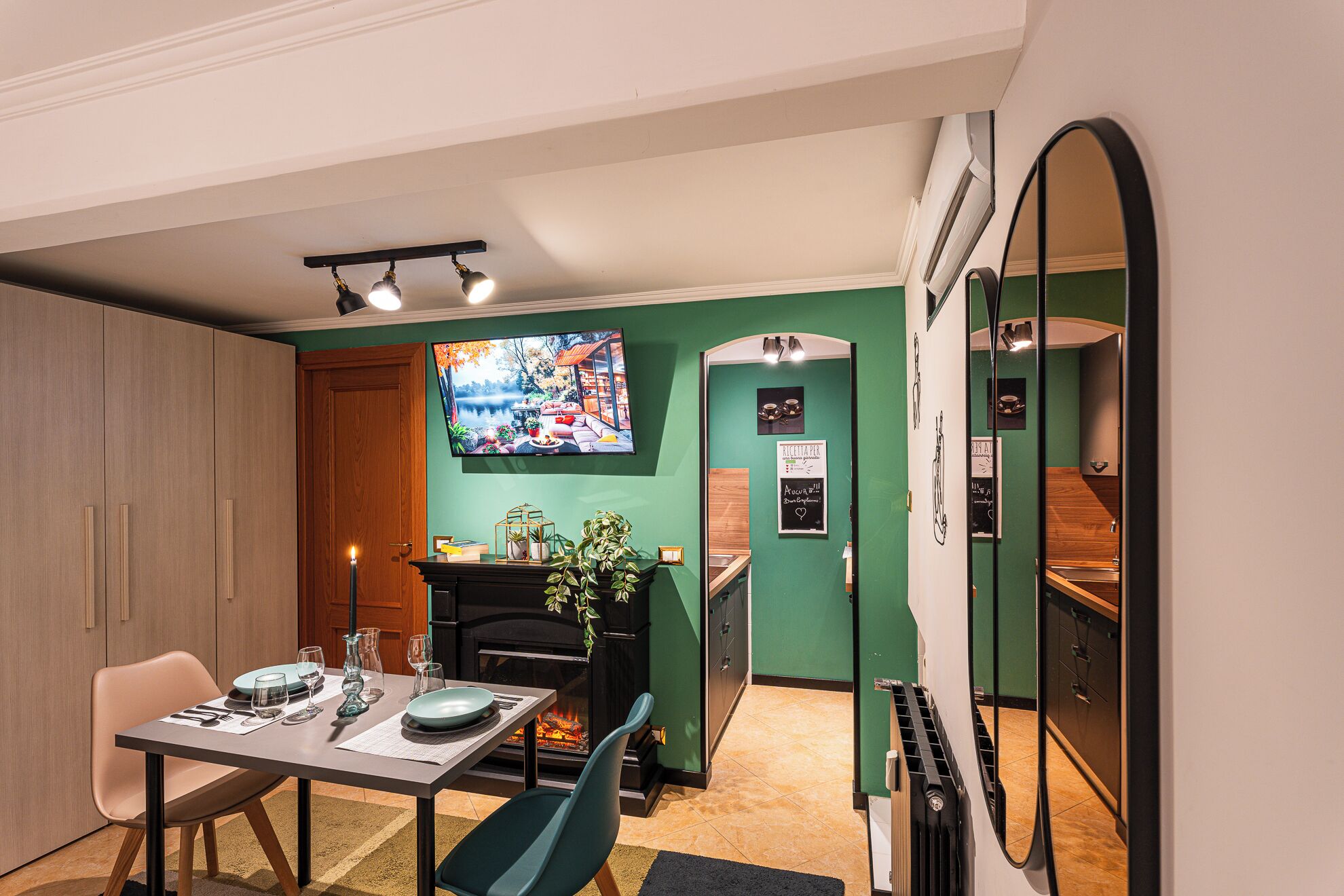 A dining area with a table set for four, a fireplace, and a television mounted on the wall.