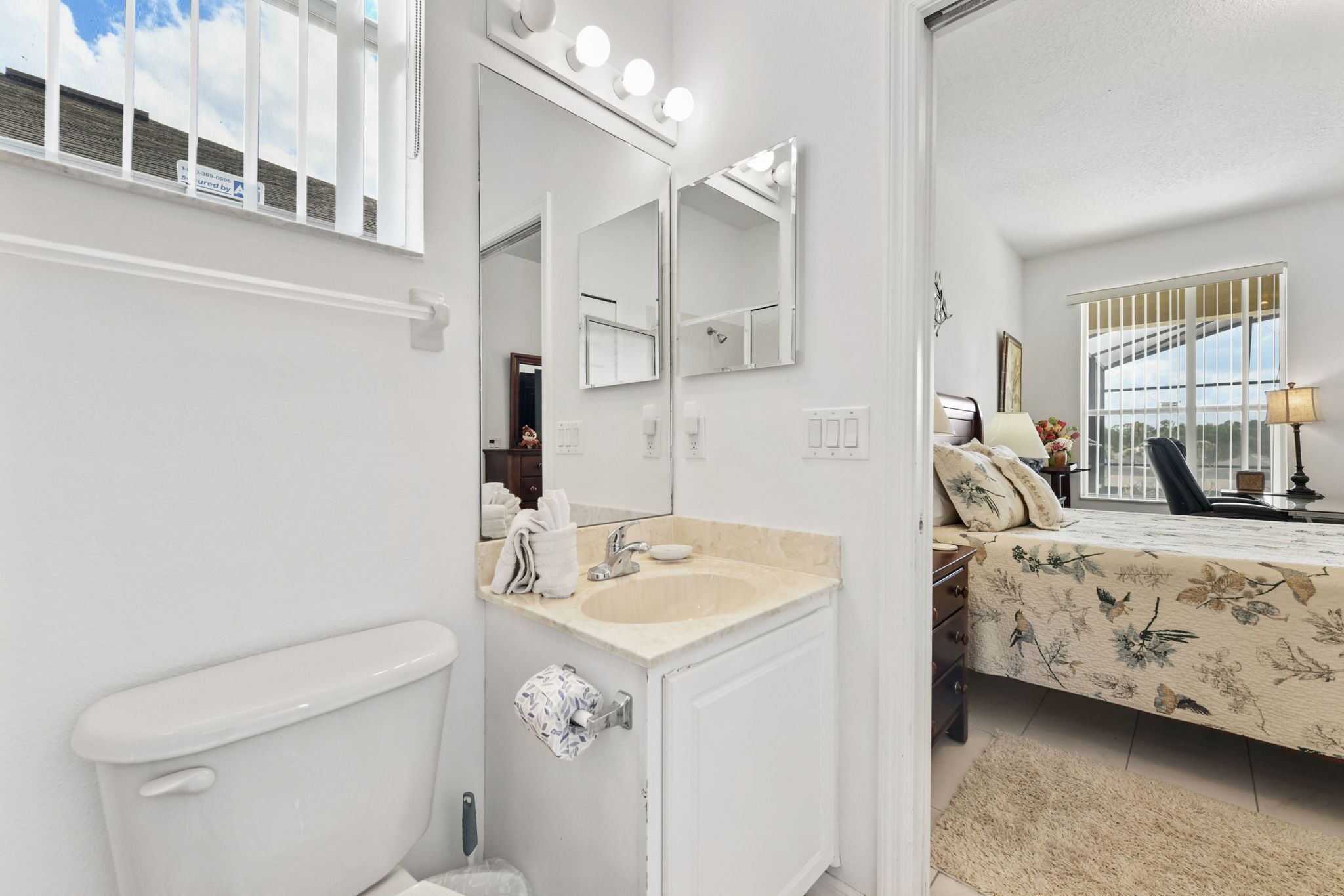 A bathroom with a toilet, sink, and mirrors.