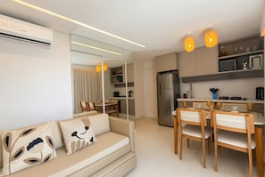 Una sala de estar moderna con sofá, comedor, cocina y un gran ventanal.