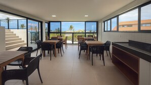 Un espace de restauration moderne doté de grandes fenêtres, de tables en bois et de chaises noires.
