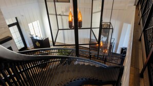 Una escalera de caracol con cerramiento de vidrio y una lámpara colgante.