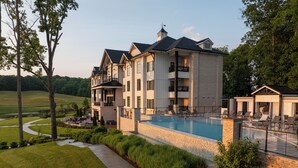 Un hotel grande de varios pisos con piscina, asientos al aire libre y un césped bien cuidado.