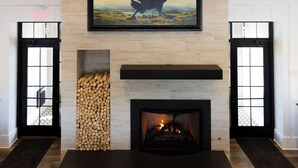 Un interior moderno con chimenea, una obra de arte grande enmarcadas de un pájaro y una lámpara circular.