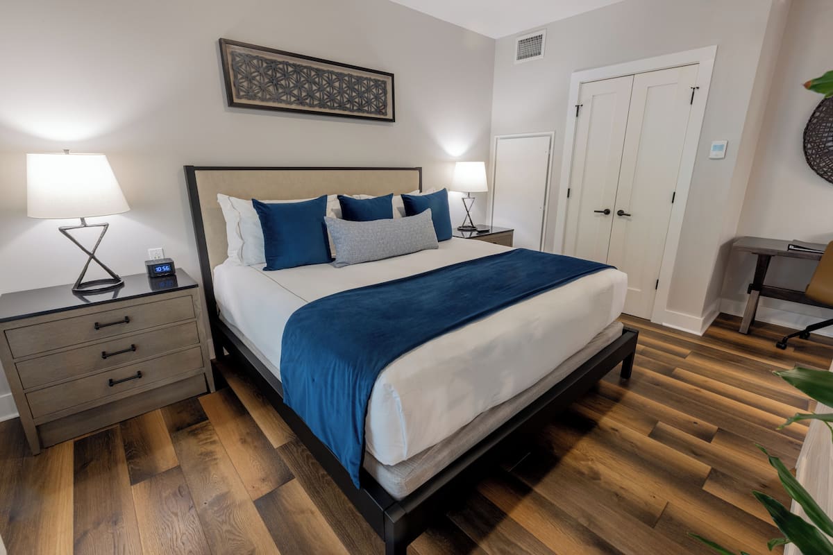Un dormitorio ordenado con cama, mesitas de noche y un buró.