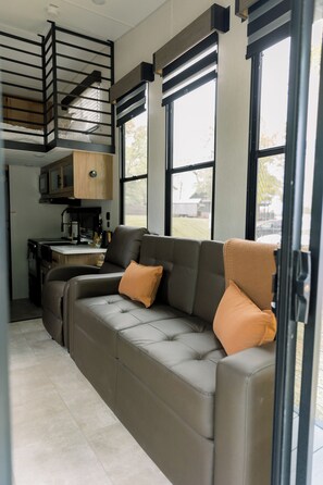Ein modernes Wohnmobil-Interieur mit einer Sitzecke, Küchenbereich und großen Fenstern.