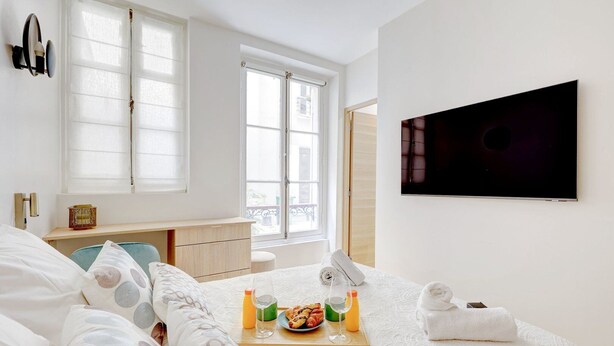 A hotel room with a bed, a desk, a TV, and a window. - 606 Aaron Suite - Apartment near the Eiffel Tower (Paris)
