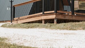 A modern building with a triangular roof, a wooden deck, and a metal railing. - Cabin 4: Reconnect with each other and nature at The Wildflower. (Princeton)