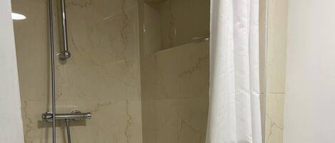 A shower area with a glass door, a showerhead, and a curtain.