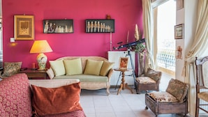 A room with a pink wall, wicker sofa, wooden armchair, and a telescope. - Secluded Villa With Private Pool, Panoramic Views (Minoa Pediada)
