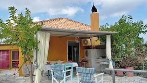 An outdoor patio with a table and chairs, a covered seating area, and a building with a tiled roof. - Secluded Villa With Private Pool, Panoramic Views (Minoa Pediada)