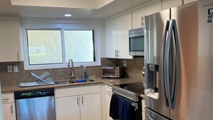 A modern kitchen with stainless steel appliances, a dishwasher, a microwave, and a window providing natural light. - 3-bedroom/3-Bathroom condo in amazing Palm Springs with mountain views! (Palm Springs)