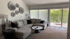 A modern living room with a sectional sofa, a round coffee table, and decorative wall art. - 3-bedroom/3-Bathroom condo in amazing Palm Springs with mountain views! (Palm Springs)