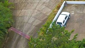 Un bâtiment doté d’un toit végétalisé, une aire de stationnement avec une voiture blanche et une allée pavée.