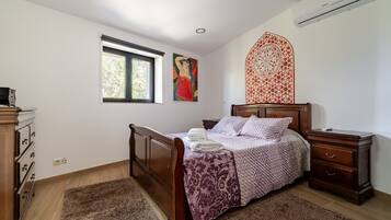 A bedroom with a wooden bed, a nightstand, a dresser, a window, and a wall decoration.