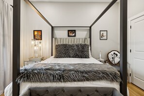 A bedroom with a four-poster bed, a bedside table with a lamp, and framed pictures on the wall. - Grand Ole View on Center Hill Lake in Smithville, TN (Smithville)