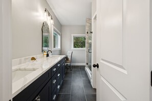 A modern bathroom with a large mirror, a vanity with drawers, a chair, and a glass shower door. - Grand Ole View on Center Hill Lake in Smithville, TN (Smithville)