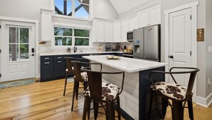 A modern kitchen with white cabinetry, a large island with bar stools, and a stainless steel refrigerator. - Grand Ole View on Center Hill Lake in Smithville, TN (Smithville)