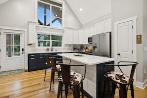 A modern kitchen with white cabinetry, a large island with bar stools, and a stainless steel refrigerator. - Grand Ole View on Center Hill Lake in Smithville, TN (Smithville)