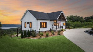A two-story house with a wrap-around porch, a well-maintained lawn, and a view of the water. - Grand Ole View on Center Hill Lake in Smithville, TN (Smithville)
