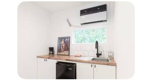 A compact kitchen with white cabinets, a black dishwasher, a window with a view of greenery, a black faucet, and an air conditioning unit. - Art-filled Cuban Studio 4 Creative Artsy Walkable Montrose Area. (Houston)