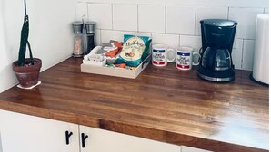 A kitchen with a wooden countertop, a potted cactus, a coffee maker, and a framed artwork above the counter. - Art-filled Cuban Studio 4 Creative Artsy Walkable Montrose Area. (Houston)