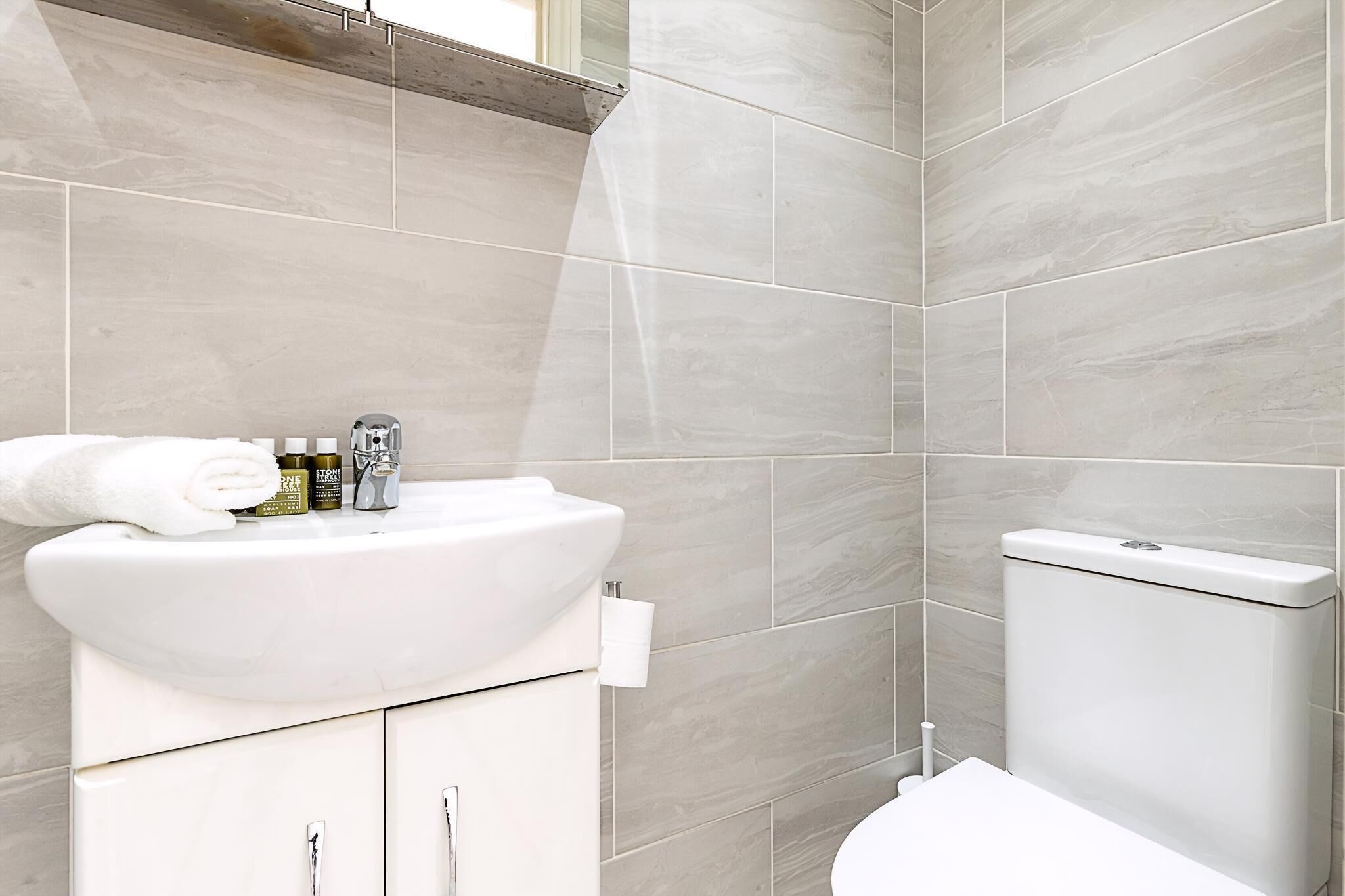 Een badkamer met een witte wastafel, toilet en betegelde wanden.