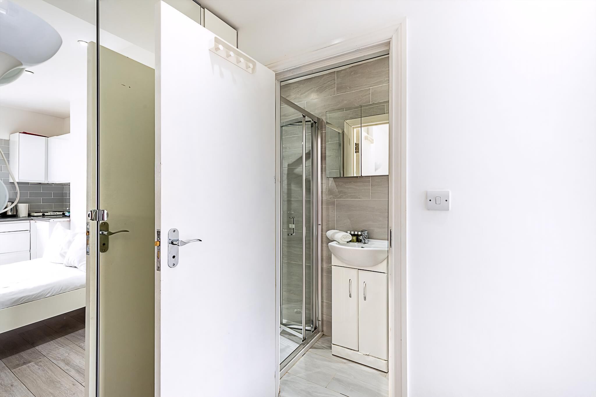 A modern bathroom with a glass shower enclosure, a white sink, and a mirror above it.