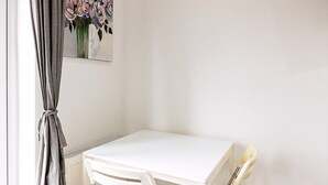 A white desk with a chair, a radiator, and a painting of flowers on the wall. - North End Hideaway (London)