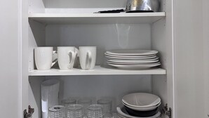 A kitchen pantry with shelves holding dishes, cups, and glassware.