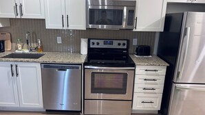 A modern kitchen with stainless steel appliances, including a microwave, oven, dishwasher, and refrigerator.