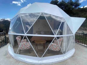 Una estructura de cúpula geodésica con una zona de estar central y vista al interior.