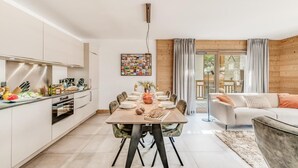 A modern kitchen with white cabinets, a dining table set for six, and a living area with a sofa and a coffee table. - View village, balcony, tv, ski locker, 68m², Champagny-en-Vanoise (Champagny-en-Vanoise)