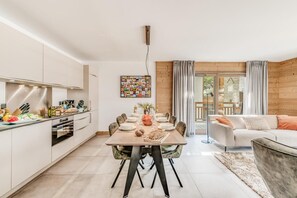 A modern kitchen with white cabinets, a dining table set for six, and a living area with a sofa and a coffee table.