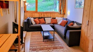 A cozy living room with a sectional sofa, a small table, and a window overlooking a green landscape. - 50m from resort center, 3rd floor, balcony, tv, 48m², Les Arcs (Les Arcs)
