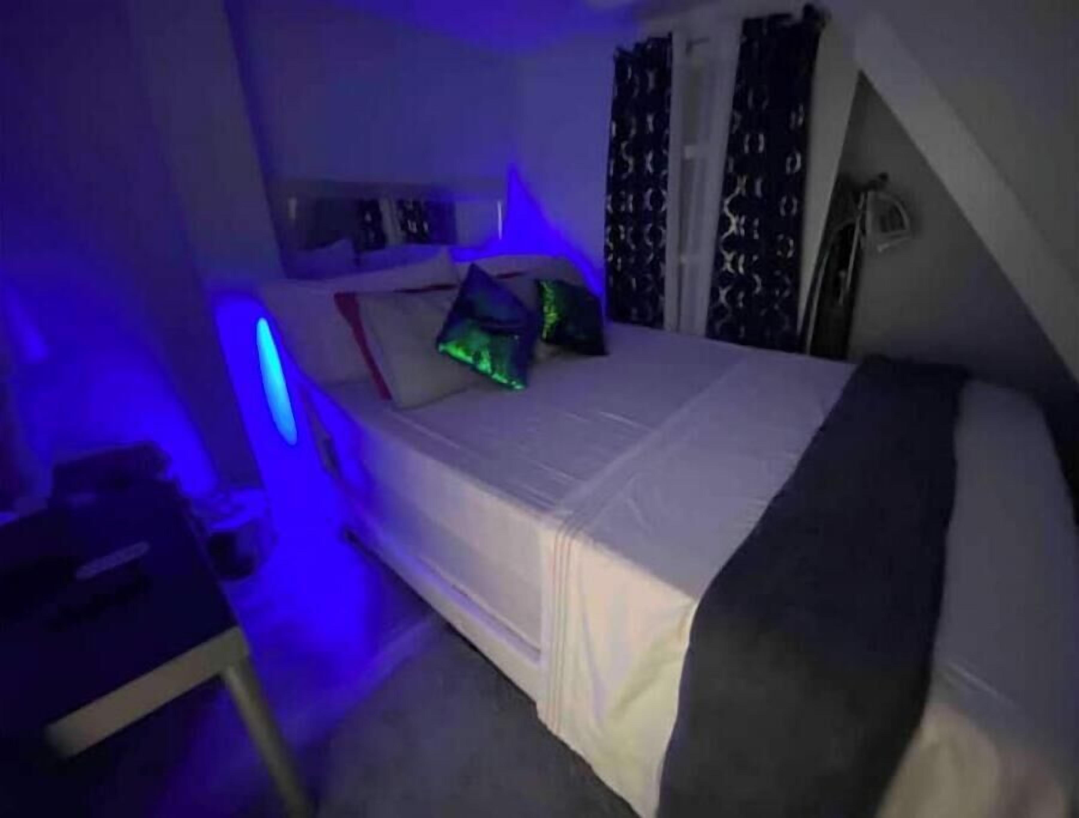 Un dormitorio con cama, almohadas y una mesita de noche.