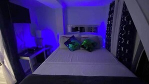 Een kleine, smalle kamer met een enkel bed, een bureau en een stoel.